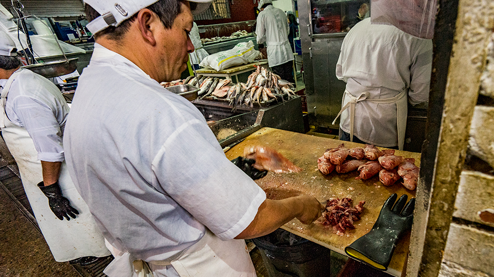 A pescadero, or fishmonger, prepares his loot for selling.