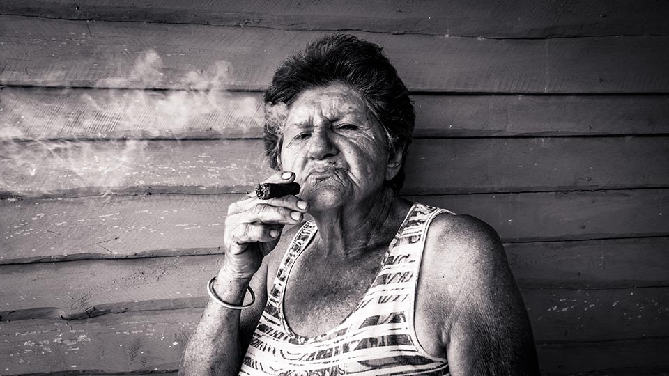 Glada, the proprietor of a small farm in Viñales, Cuba, enjoys a cigar produced here at her farm.